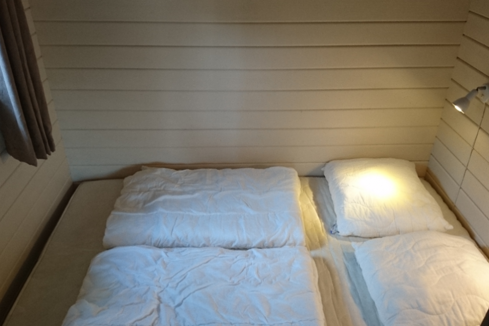 Soveværelse med dobbeltseng i hytte på campingplads i Nordjylland